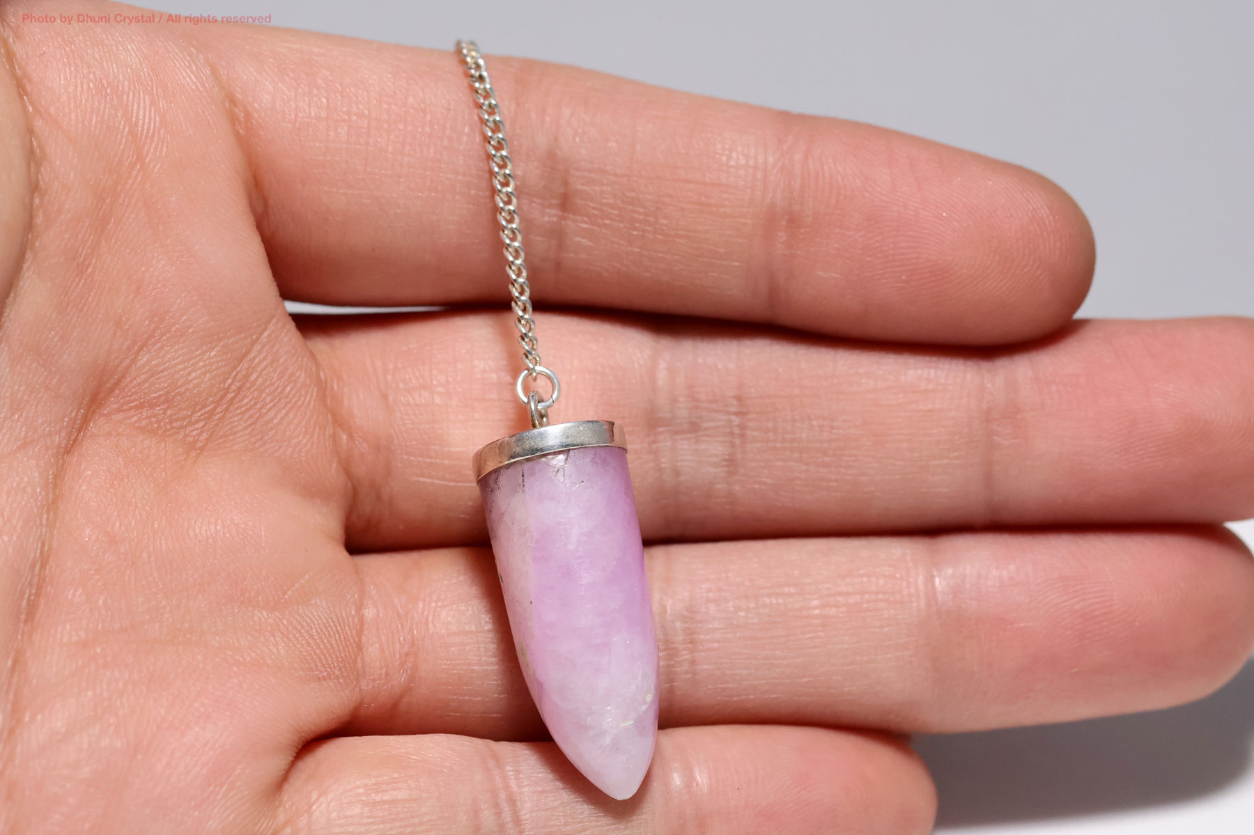 クンツァイトペンジュラム手の上の画像